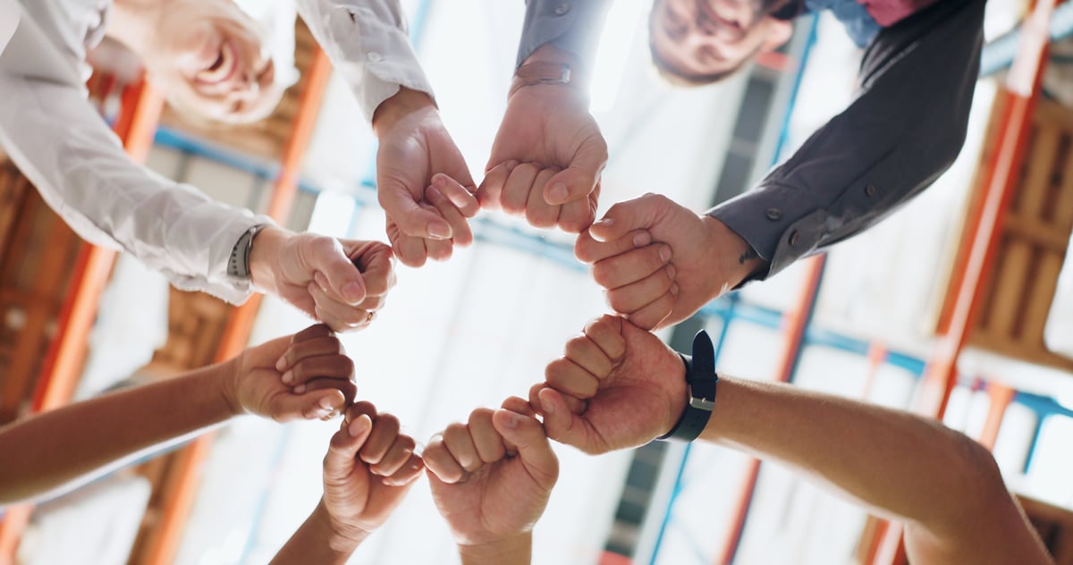 Equipo de trabajo uniendo manos en señal de colaboración y confianza
